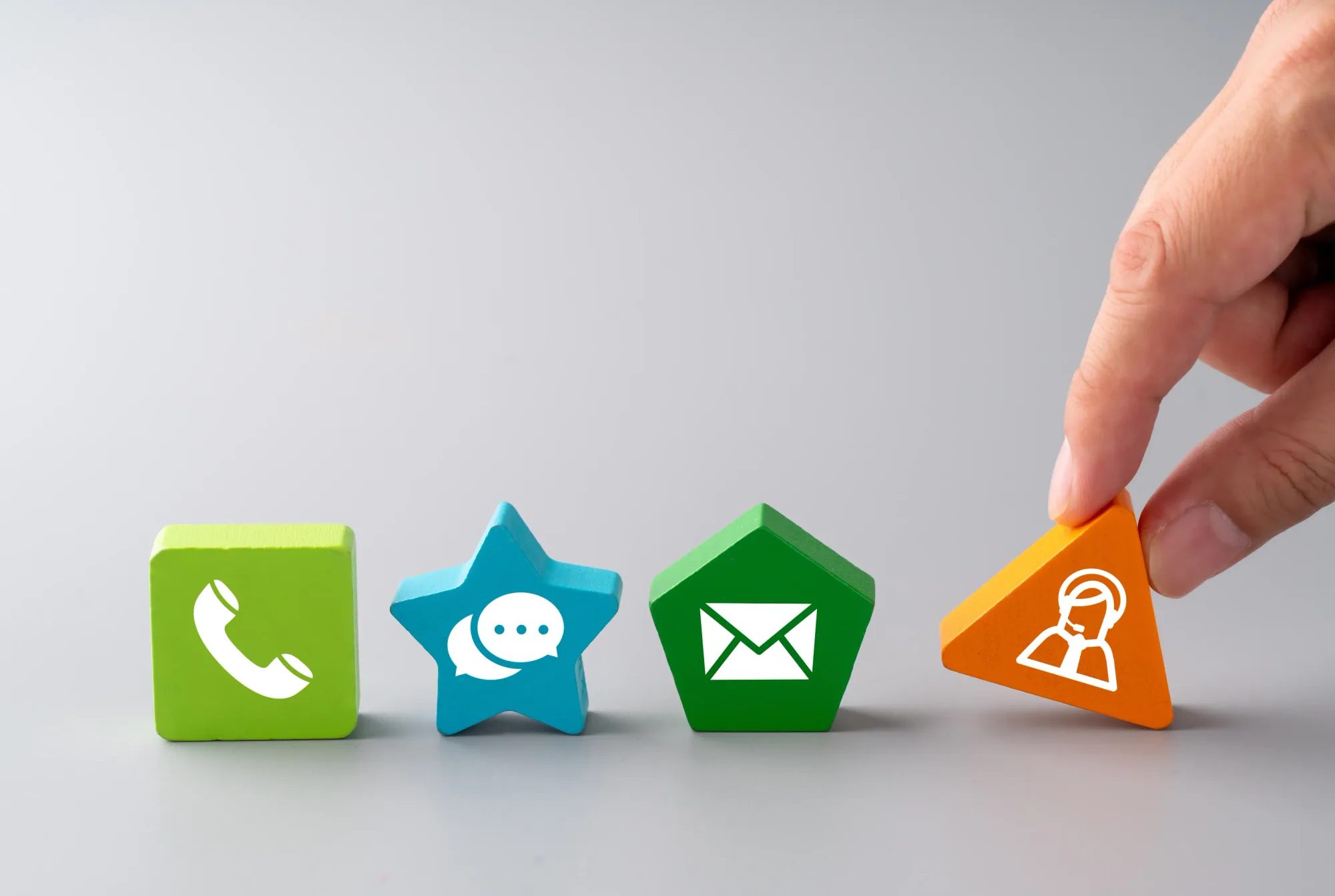 Four coloured wooden shapes carrying telephone, message, envelope and support icons arranged in a row.