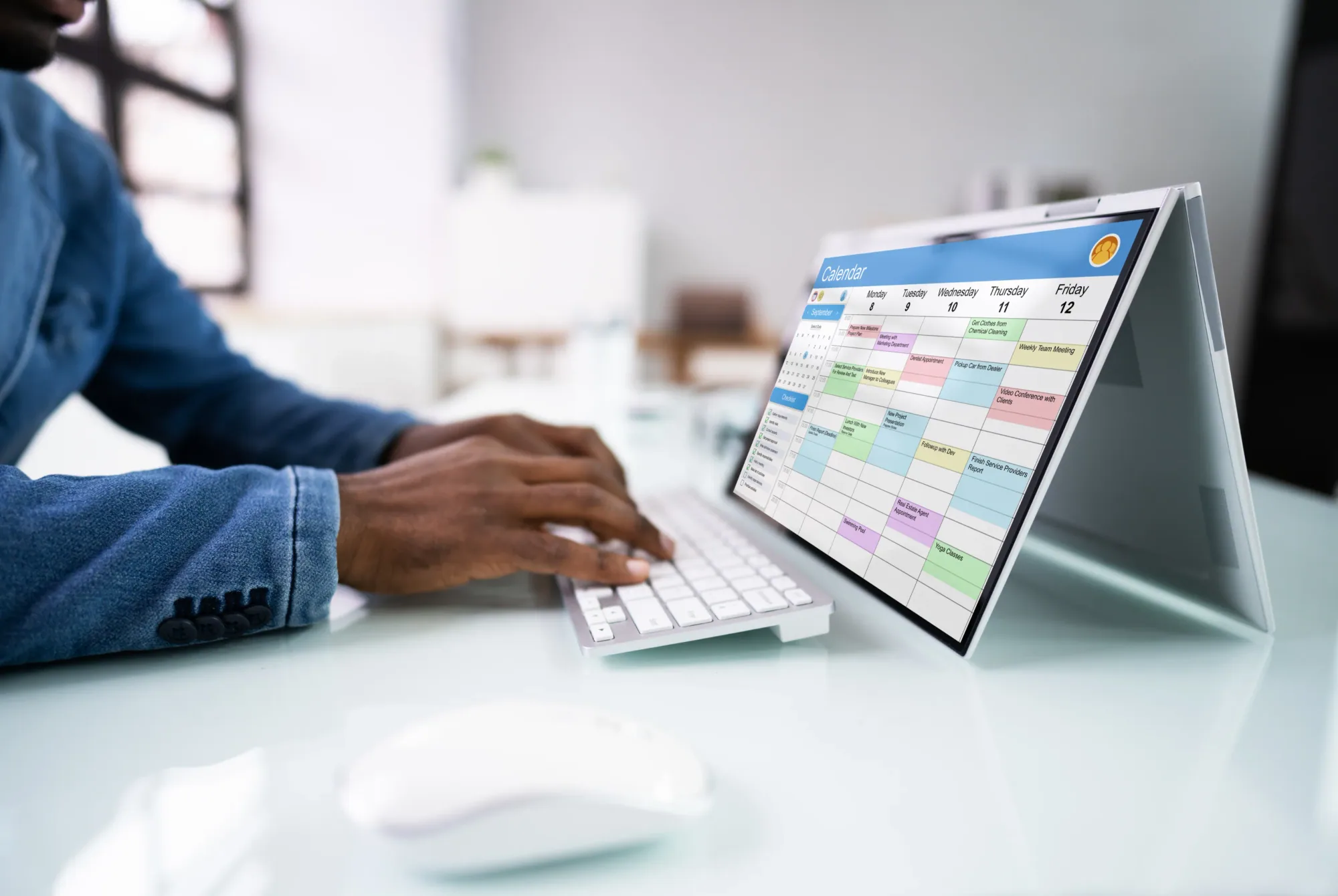 A person at a desk reviewing a weekly calendar on a laptop screen while planning ahead.